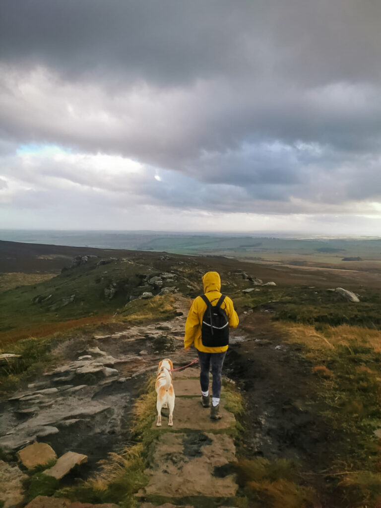 Girl walking dog in hills in yelllow coat
